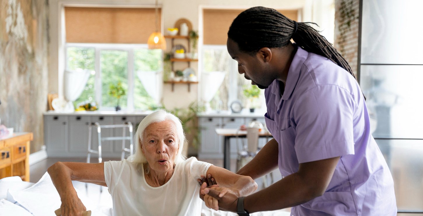 A caregiver helping a client sit up in bed and reach for her walking cane