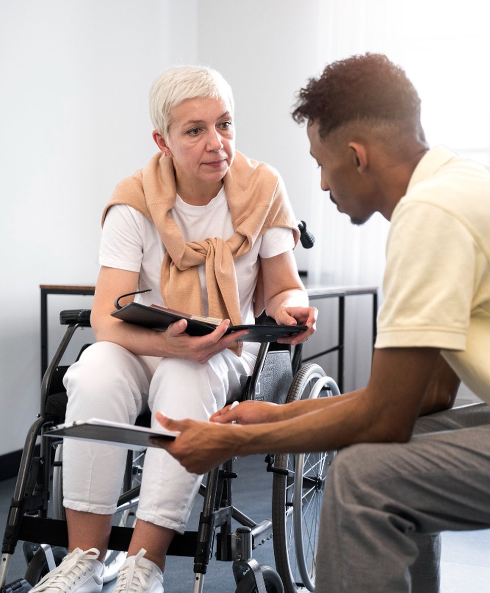 A caregiver talking with a client in a wheelchair at eye level